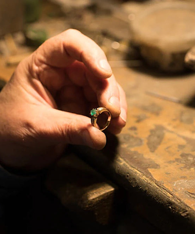 A finished emerald ring being inspected by hand