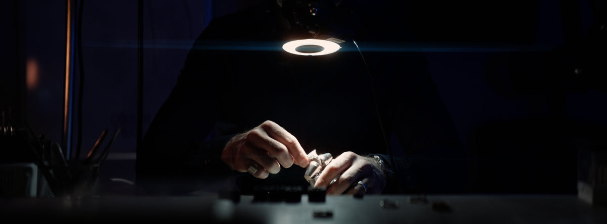 A Hamlington's jeweller at the workbench under a ring light, setting a stone by hand